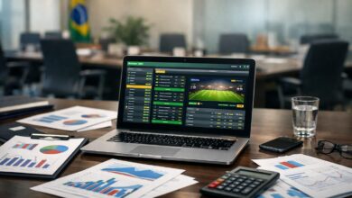 FEBRALOT critica suspensão da BetCaixa e alerta para avanço do mercado ilegal 1 imagem de um computador, com apostas no fundo e papeis contabeis na mesa com uma calculadora