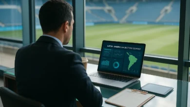 Vista de costas de um profissional diante de um laptop com painel de apostas genérico; campo de futebol ao f